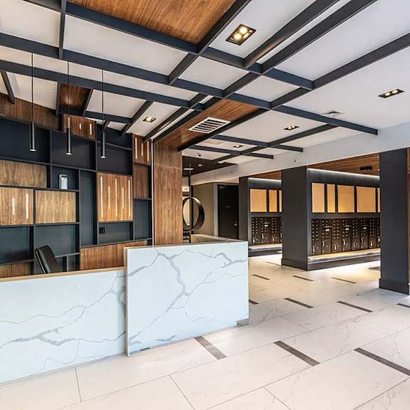 a modern office lobby with a white marble reception desk and wooden accents.