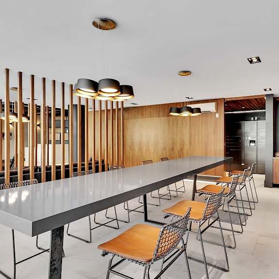 a long table with chairs is surrounded by wooden slats on the wall.