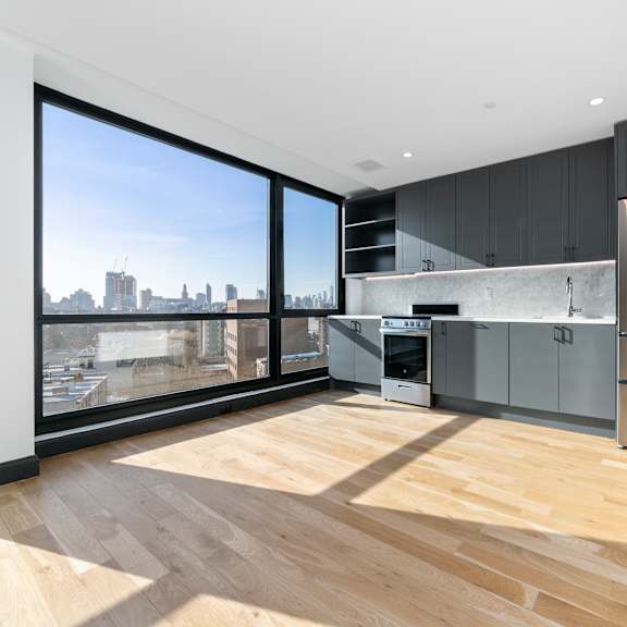 a modern kitchen with wooden floors and a city view through the windows.