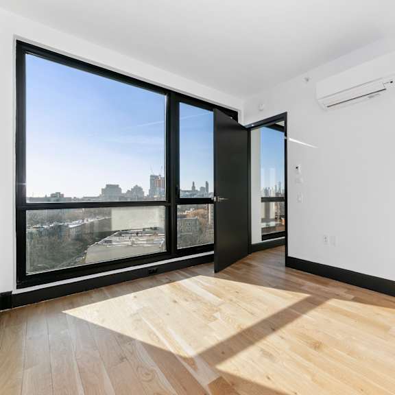 a room with a wooden floor and a large window overlooking a cityscape.
