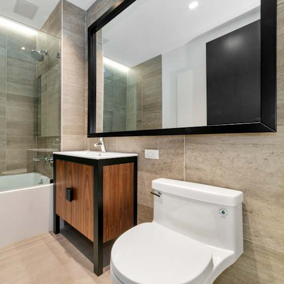 a modern bathroom with a white bathtub, wooden cabinet, and a white toilet.