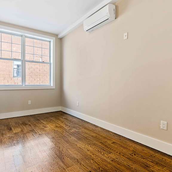 a room with a window and wooden flooring.