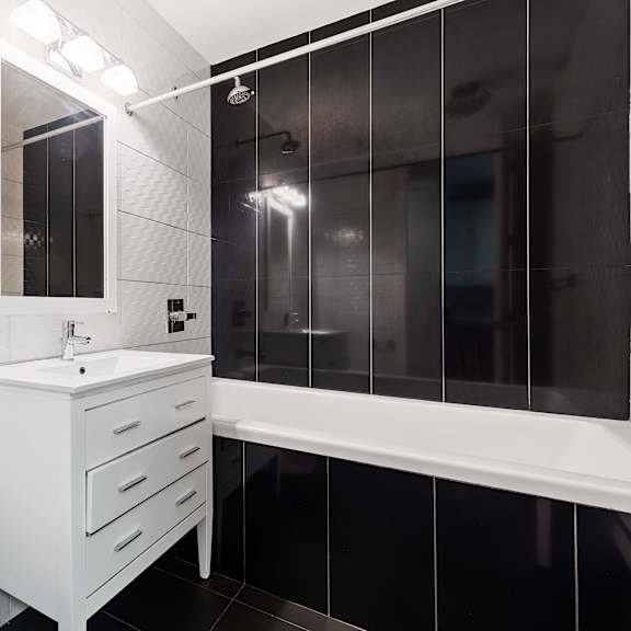 a white bathroom with a tub, sink, and mirror.