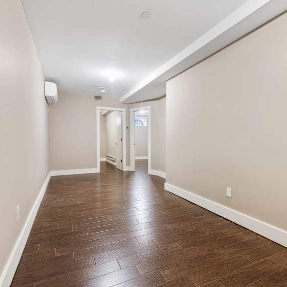a long hallway with wood floors and white walls.
