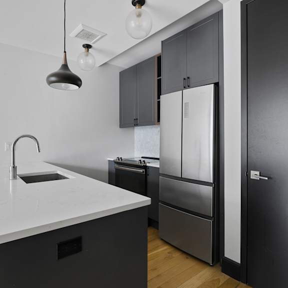 a modern kitchen with a white countertop and black cabinets.