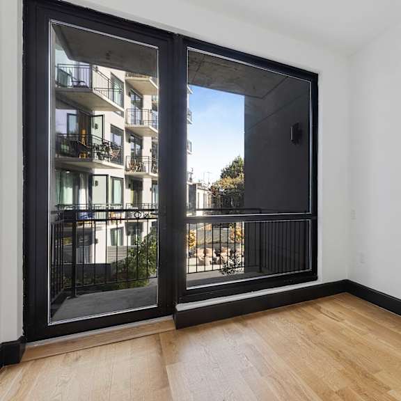 a room with a sliding glass door leading to a balcony with a railing.