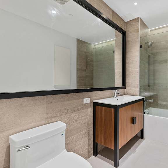 a modern bathroom with a white toilet and a wooden vanity.