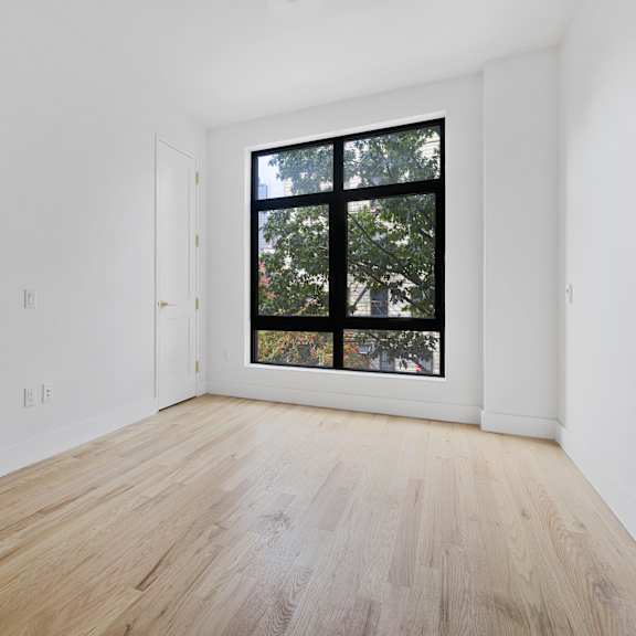 a room with white walls and a large window and wooden floors