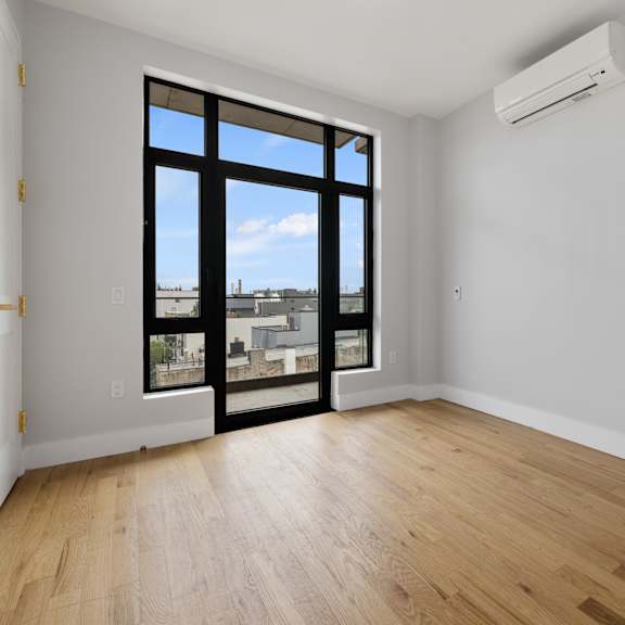 an empty living room with a large window and wooden floors