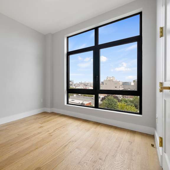 an empty room with a large window and wooden floors
