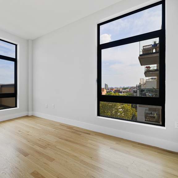 an empty living room with large windows and a wooden floor