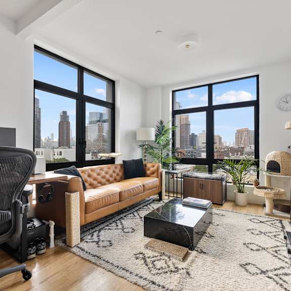 an open living room with a couch and a desk with a large window
