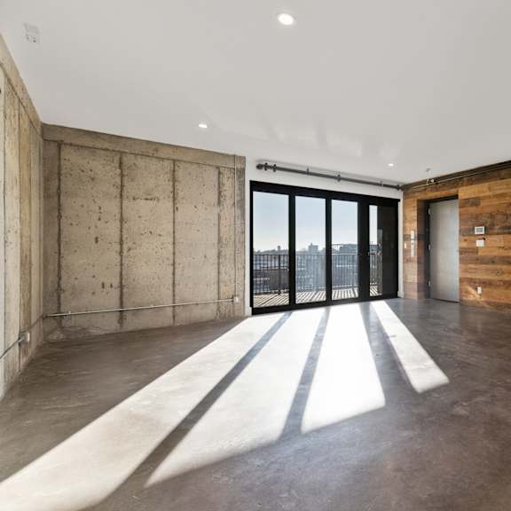 a room with a concrete wall and a sliding glass door.