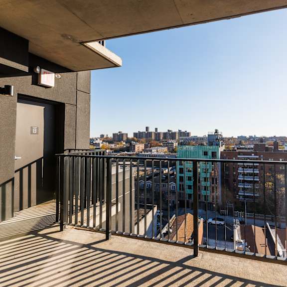 a balcony with a metal railing and a view of a city skyline.
