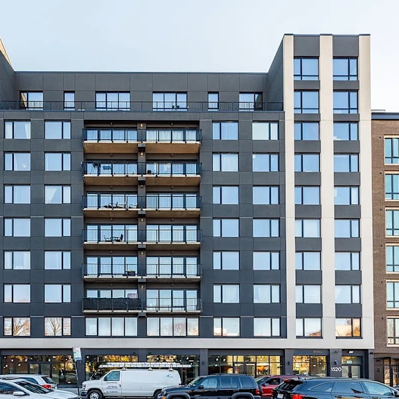 a large modern building with a lot of windows and cars parked in front.