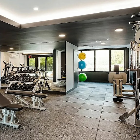 a gym with a bench, weights, and exercise balls.