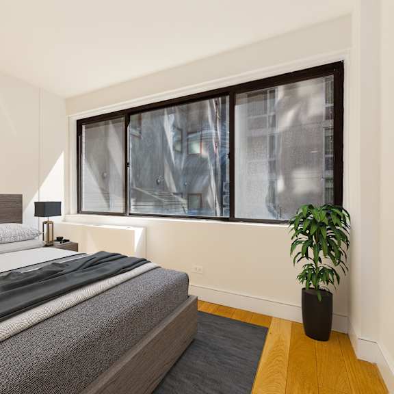 a bedroom with a bed, two pictures on the wall, a potted plant, and a window with a view of a building outside.