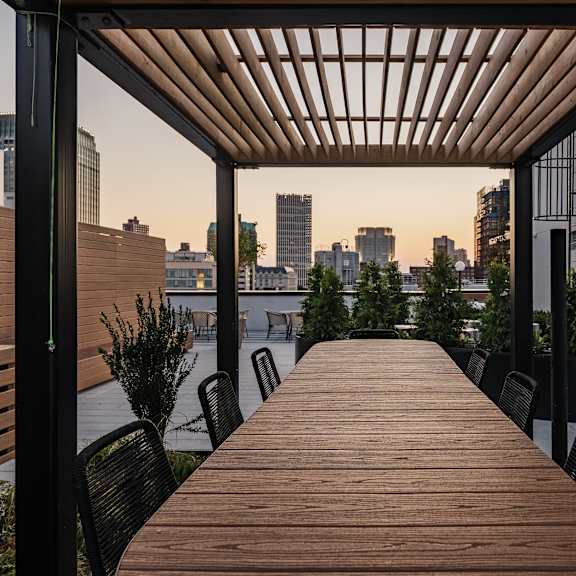 a long wooden table on a balcony with a view of the city
