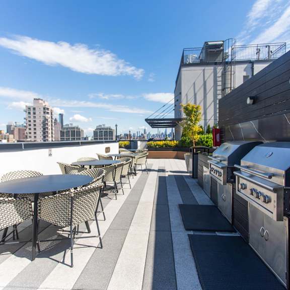 rooftop terrace with grills and dining area at 260 gold apartments, new york