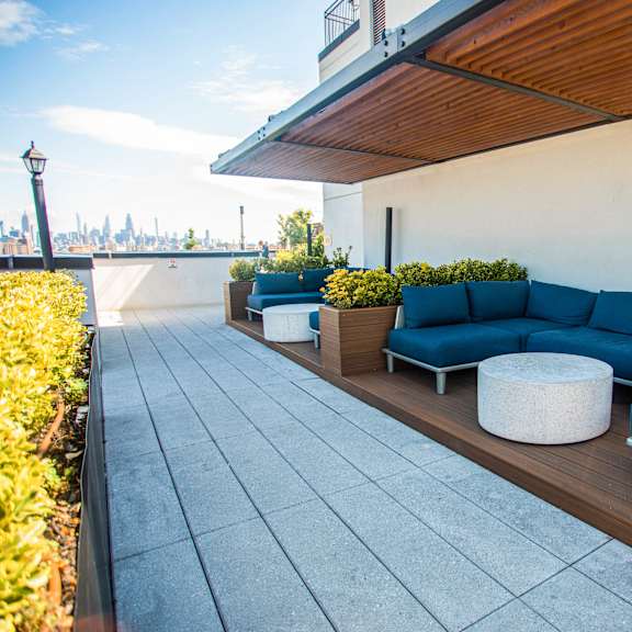 rooftop lounge with blue sectional seating and skyline views at 260 gold apartments, brooklyn, ny 11201