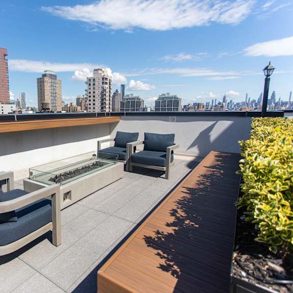 rooftop terrace seating with fire table and city skyline at 260 gold apartments, brooklyn, ny