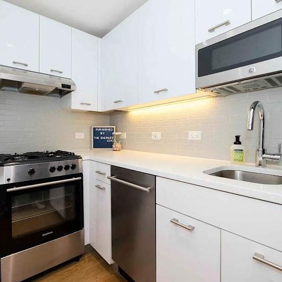 a modern kitchen with white cabinets and stainless steel appliances.