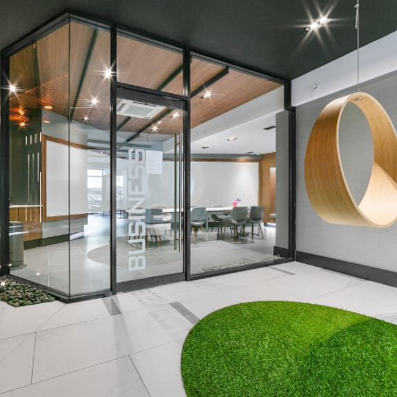 a modern office lobby with a glass wall and a green grass area.