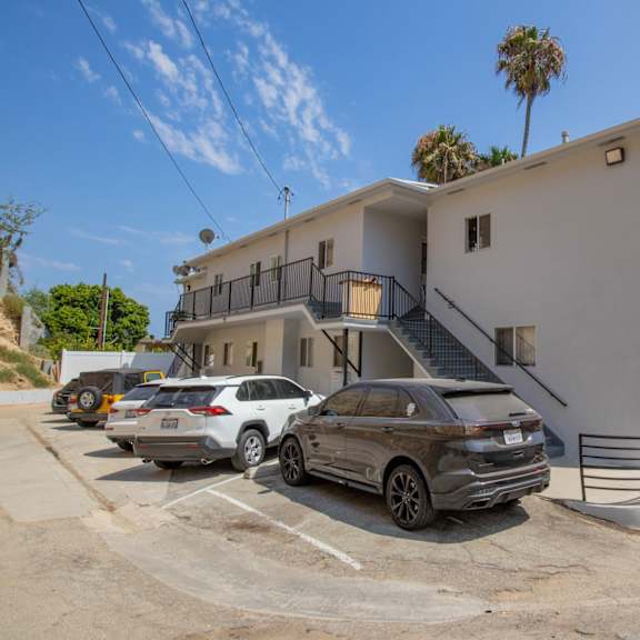 the front of a white building with cars parked outside