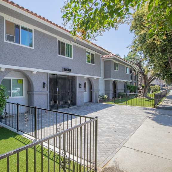 a white house with a sidewalk and a fence in front of it