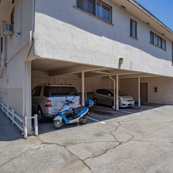 a parking garage with two cars and a scooter in front of a building