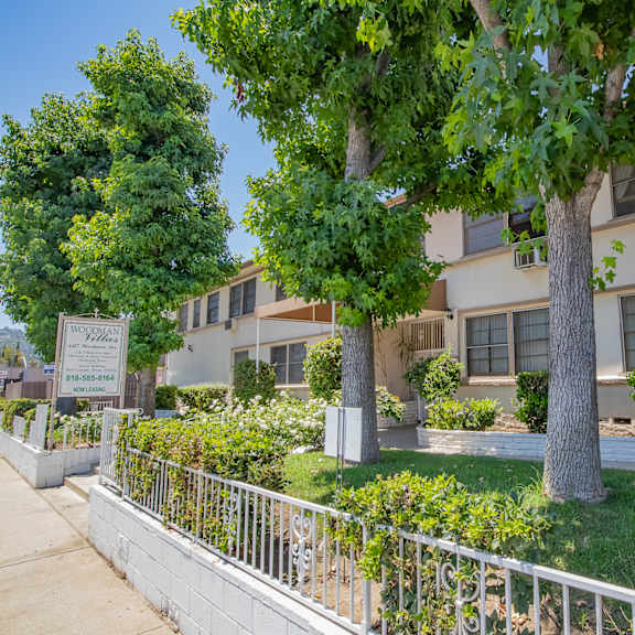 an apartment building with a yard and trees in front of it