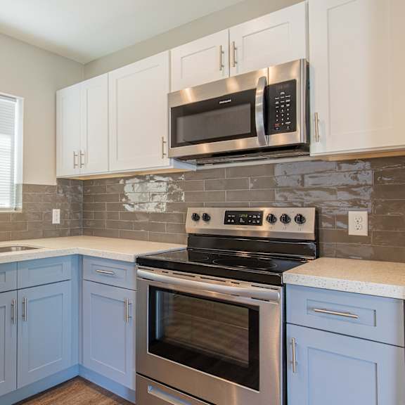 a kitchen with blue cabinets and stainless steel appliances