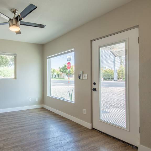 an empty living room with a ceiling fan
