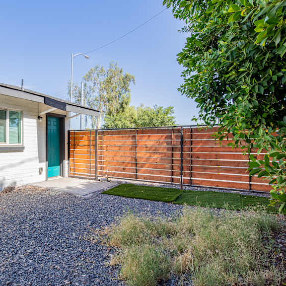 a small white house with a blue door and a wooden fence
