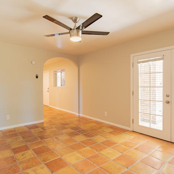 an empty living room with a ceiling fan and french doors