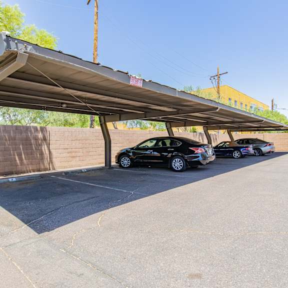 a parking lot with three cars under a metal awning