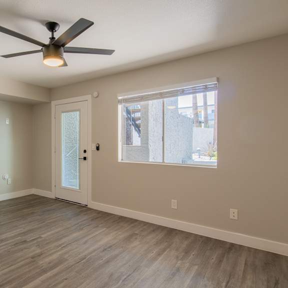 an empty bedroom with a ceiling fan and a window