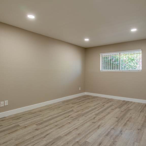 a bedroom with hardwood floors and beige walls