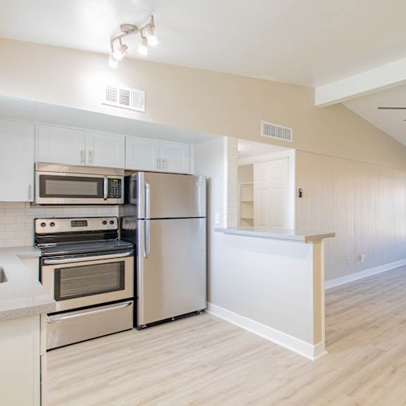 an empty kitchen and living room with a ceiling fan
