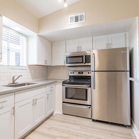 a kitchen with white cabinets and stainless steel appliances