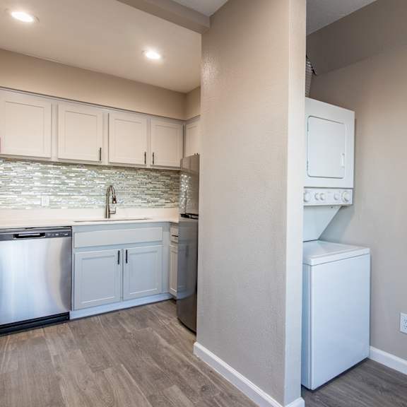 a kitchen with white cabinets and a white washer and dryer  at sofia apartments, tempe