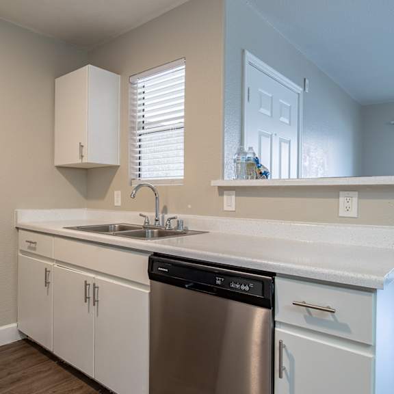 a kitchen with white cabinets and a stainless steel dishwasher