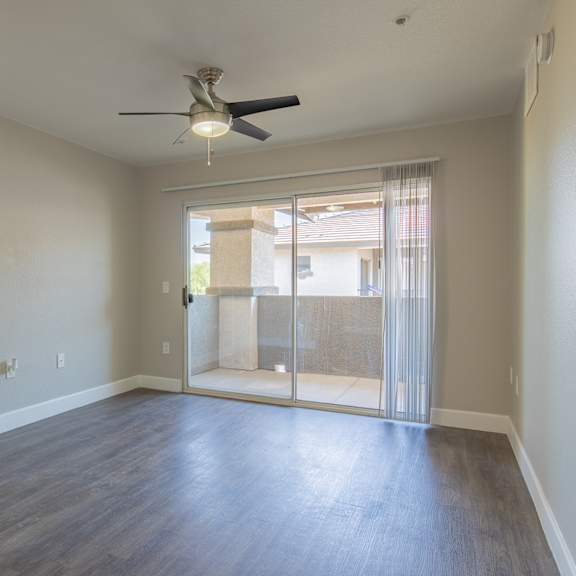 an empty living room with a ceiling fan