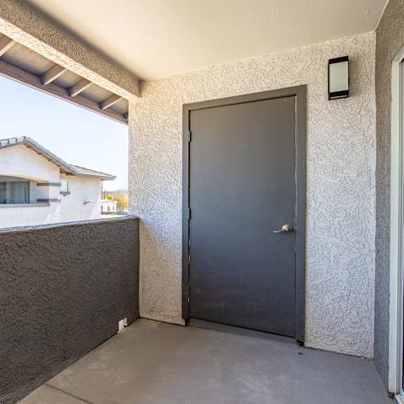 the front door of a home with a black door and a balcony