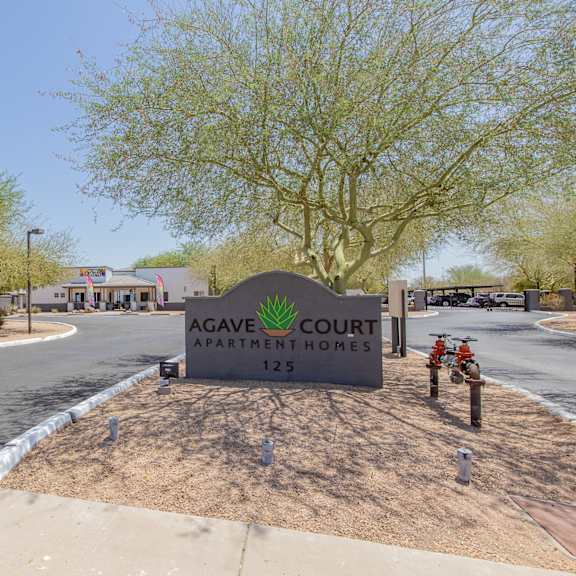 a sign that says agave court apartments with a building in the background