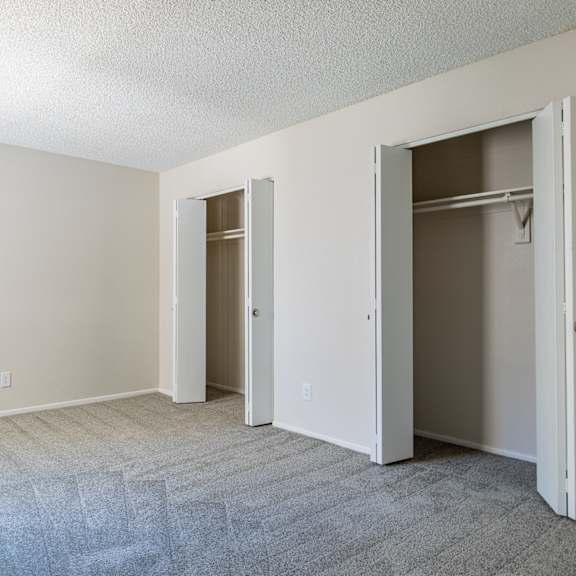 a bedroom with a carpeted floor and two closets  at sofia apartments, tempe, 85283