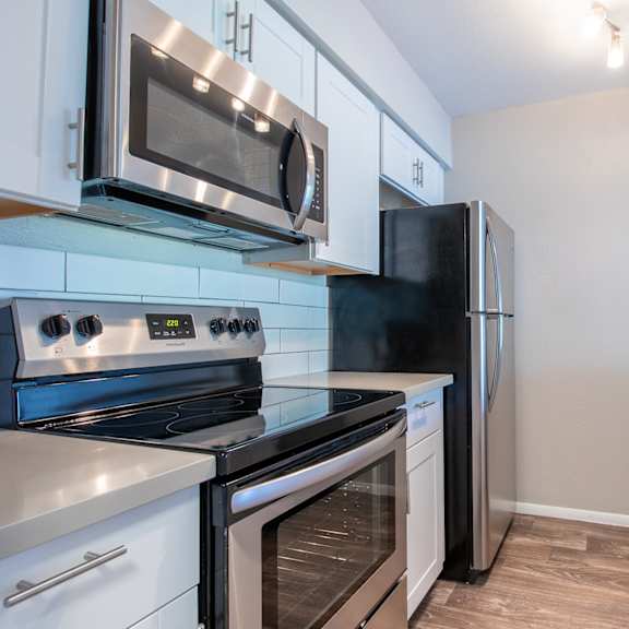 a kitchen with white cabinets and stainless steel appliances