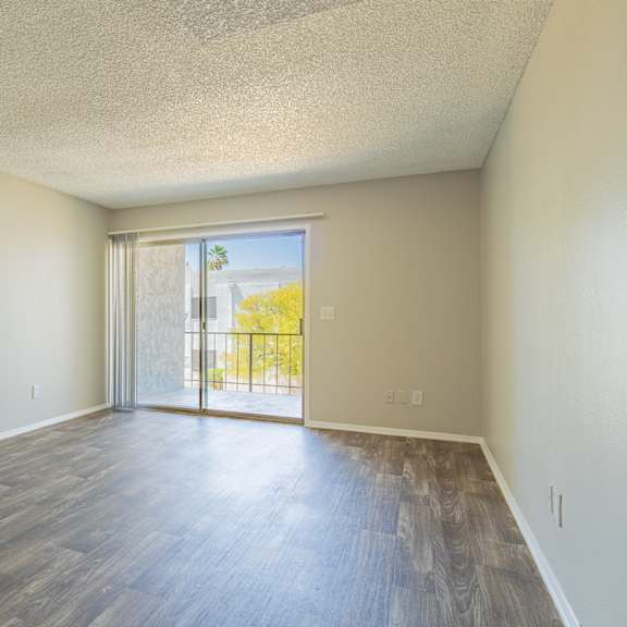 a bedroom with hardwood flooring and a sliding glass door leading to a balcony