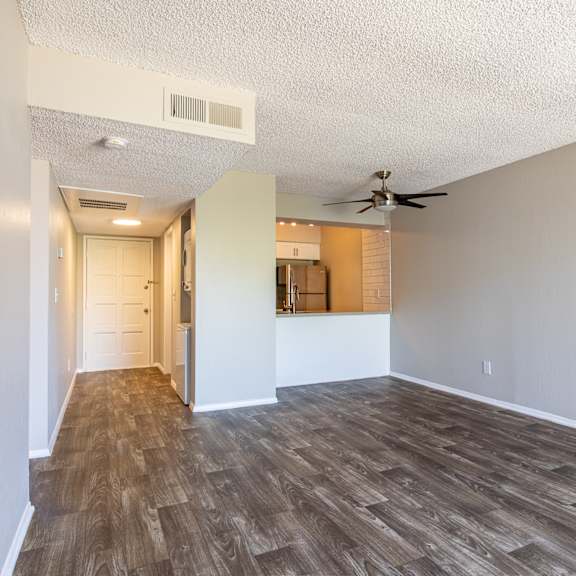 an empty living room with a ceiling fan