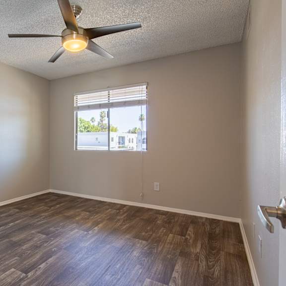 an empty bedroom with a ceiling fan and a window